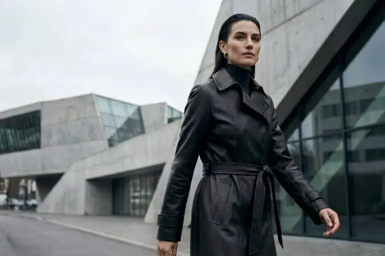 woman walking in an empty city wearing a long leather coat, titled leather endures